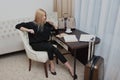 Young blonde woman sitting at a table in a hotel room. Freelancer on a business trip. Travel and business travel concept