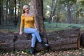 Young blonde woman sitting on a tree branch in the forest Royalty Free Stock Photo