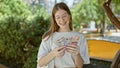 Young blonde woman smiling confident counting swedish krone banknotes at park