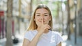 Young blonde woman smiling confident doing silent gesture at street