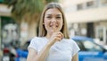 Young blonde woman smiling confident doing silent gesture at street