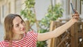 Young blonde woman smiling confident making selfie by the smartphone at coffee shop terrace Royalty Free Stock Photo