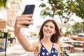 Young blonde woman smiling confident making selfie by the smartphone at coffee shop terrace Royalty Free Stock Photo