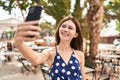 Young blonde woman smiling confident making selfie by the smartphone at coffee shop terrace Royalty Free Stock Photo