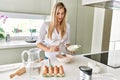 Young blonde woman smiling confident pouring flour on bowl at kitchen Royalty Free Stock Photo