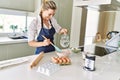 Young blonde woman smiling confident pouring water on bowl at kitchen Royalty Free Stock Photo