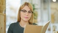 Young blonde woman smiling confident reading book at coffee shop Royalty Free Stock Photo