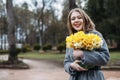Young blonde woman smiling outdoors with a bouquet of yellow flowers Narcissus Royalty Free Stock Photo