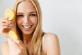 Young blonde woman smiling while posing with piece of lemon