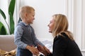 A young blonde woman squatted down in front of her son and held his hands