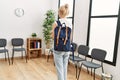 Young blonde woman standing backwards looking clock at waiting room