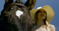 Young blonde woman is standing near horse, close-up of animal muzzle