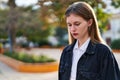 Young blonde woman standing with serious expression looking down at park Royalty Free Stock Photo