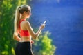 Young blonde woman stands on a blue sea background with a mobile phone. A sporty woman uses a phone near the sea Royalty Free Stock Photo