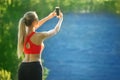 Young blonde woman stands on a blue sea background. Sports woman in red t-shirt makes selfie on nature near the sea Royalty Free Stock Photo