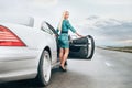 Young blonde woman stay near car on lonely highway Royalty Free Stock Photo