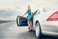 Young blonde woman stay near car on lonely highway Royalty Free Stock Photo