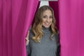 Young blonde woman stepping out from behind pink curtains in a dressing room Royalty Free Stock Photo