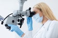 Young blonde woman stomatologist looking at dental microscope