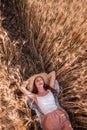 Young blonde woman in straw hat on the background of field of golden spikelets of wheat, rye. Close-up portrait of beautiful girl Royalty Free Stock Photo