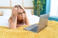 Young blonde woman stressed using laptop lying on bed at bedroom Royalty Free Stock Photo