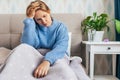 Young blonde woman suffering of depression sitting n bed on in warm sweater. Loneliness, sadness, divorse Royalty Free Stock Photo