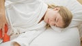Young blonde woman suffering for menstrual pain lying on bed at bedroom Royalty Free Stock Photo