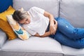 Young blonde woman suffering for menstrual pain lying on sofa at home Royalty Free Stock Photo