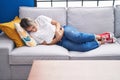 Young blonde woman suffering for menstrual pain lying on sofa at home Royalty Free Stock Photo