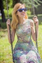 Young blonde woman swinging on a bright sunny day Royalty Free Stock Photo