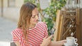 Young blonde woman taking photo to cup of coffee by smartphone at coffee shop terrace Royalty Free Stock Photo