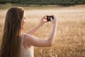 Blonde young woman taking photos in the field with her mobile phone Royalty Free Stock Photo