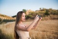 Blonde young woman taking photos in the field with her mobile phone Royalty Free Stock Photo