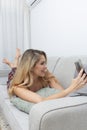 pretty blonde woman taking photos with her smart-phone on the sofa in her living room Royalty Free Stock Photo