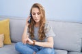 Young blonde woman talking on the smartphone looking watch at home Royalty Free Stock Photo