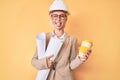 Young blonde woman with tattoo holding paper blueprints drinking take away cup of coffee sticking tongue out happy with funny Royalty Free Stock Photo