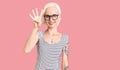 Young blonde woman with tattoo wearing casual clothes and glasses showing and pointing up with fingers number four while smiling Royalty Free Stock Photo