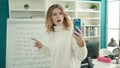 Young blonde woman teacher having video call explaining maths exercise at university classroom