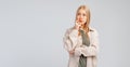 Young blonde woman with thoughtful face touching chin, thinking, making decision, standing in casual clothes over grey background Royalty Free Stock Photo