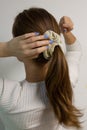 Young, blonde woman touching beige scrunchie on her sleek ponytail. Royalty Free Stock Photo