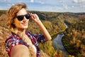 Young blonde woman tourist on a cliff taking selfie picture on