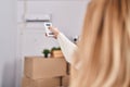 Young blonde woman using air condition machine at new home Royalty Free Stock Photo