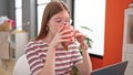 Young blonde woman using laptop drinking coffee at dinning room Royalty Free Stock Photo