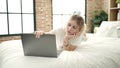 Young blonde woman using laptop lying on bed at bedroom Royalty Free Stock Photo