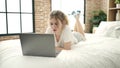 Young blonde woman using laptop lying on bed at bedroom Royalty Free Stock Photo