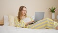 Young blonde woman using laptop lying on bed at bedroom Royalty Free Stock Photo