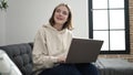 Young blonde woman using laptop sitting on sofa at home Royalty Free Stock Photo