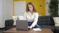 Young blonde woman using laptop sitting on sofa at home Royalty Free Stock Photo