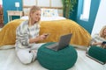 Young blonde woman using laptop and smartphone sitting on floor at bedroom Royalty Free Stock Photo