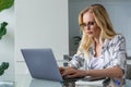 young blonde woman using laptop while working